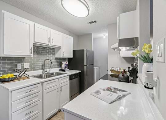 A kitchen with white cabinets and a white countertop.