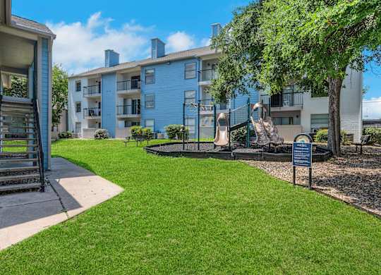 A blue apartment building with a green lawn in front.
