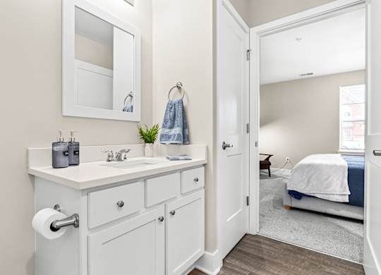 a bathroom with a sink and a mirror and a door to a bedroom