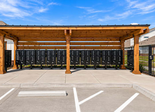 A parking lot with a wooden canopy and a row of black mailboxes.