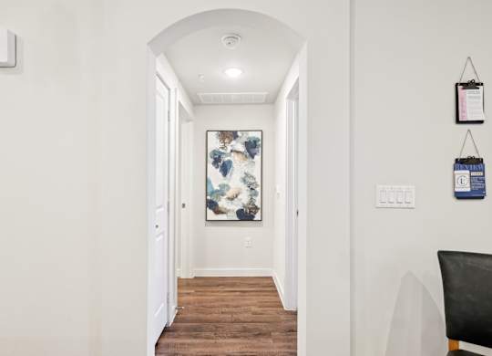 A hallway with a chair and a painting on the wall.
