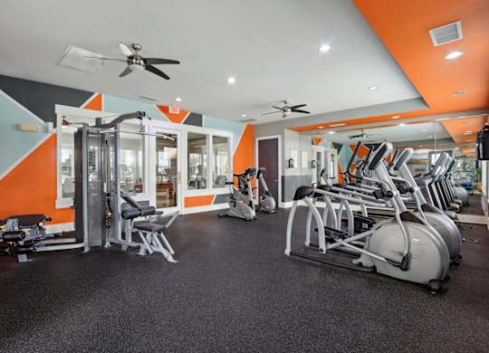 A gym with orange walls and a variety of equipment.