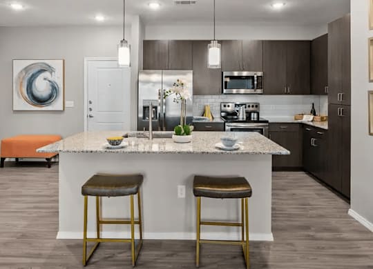 A modern kitchen with a white island and two stools.