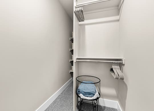 a walk in closet with a wicker basket and a shelf with folded towels