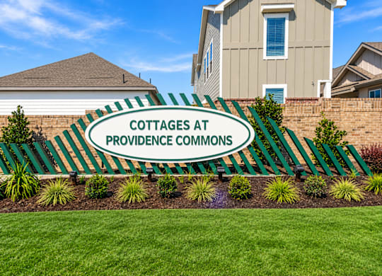 A sign that says Cottages at Providence Commons in front of a building.