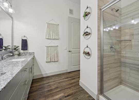 Spacious bathroom with tiled standing shower, large countertops, and bright lighting.