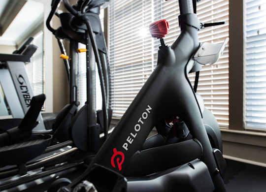 A Peloton bike is in a room with a window.