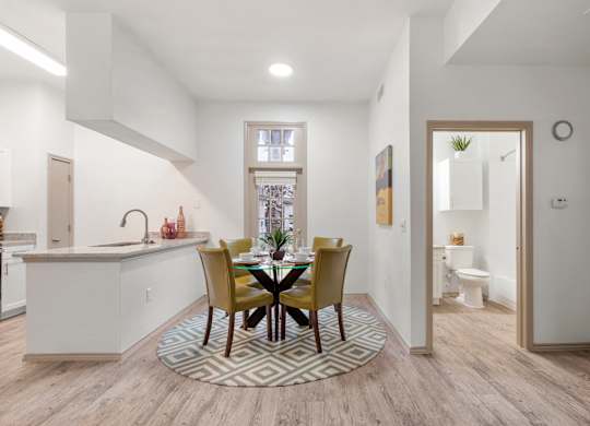 A kitchen with a dining table and chairs in the middle.