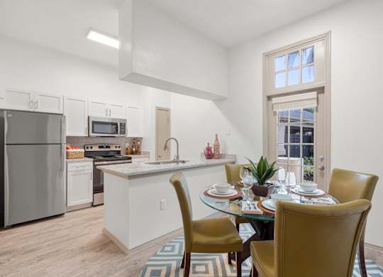 A kitchen with a table set for two with a window in the background.