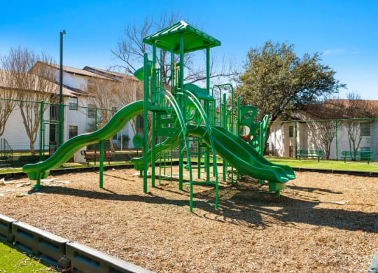 a playground with a green playset in a park