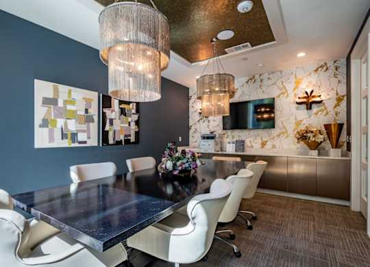A modern dining room with a dark table and white chairs.