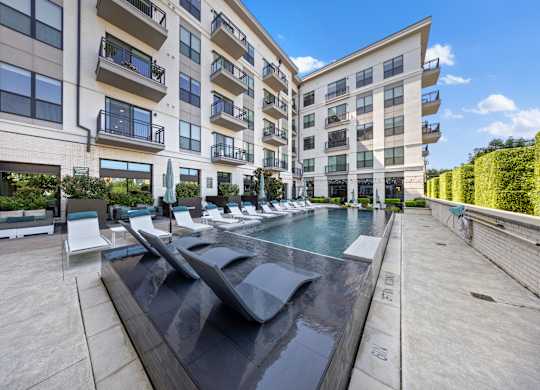 A modern apartment complex with a pool in the foreground.