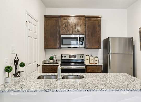 A kitchen with a granite countertop and stainless steel appliances.