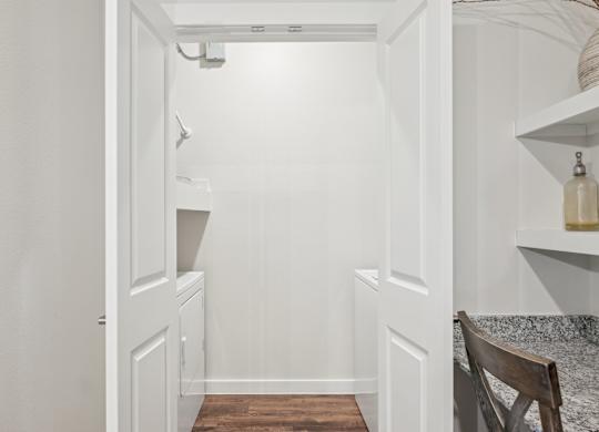 A white hallway with a wooden floor and a chair on the right side.