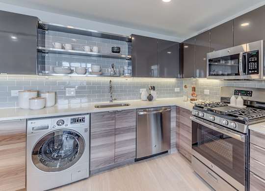 A modern kitchen with a washing machine and a microwave oven.