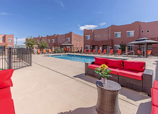 A pool area with red couches and a table with flowers on it.