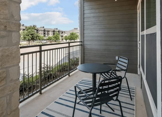 A balcony with a table and chairs overlooking a street.