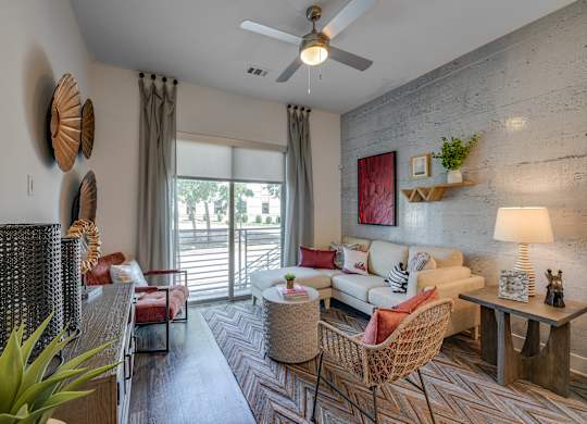 A living room with a sofa, chairs, and a ceiling fan.