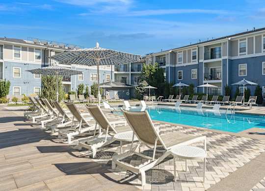 A row of sun loungers are set up by a pool.