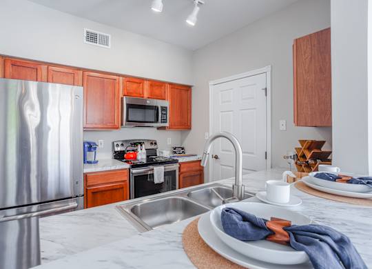 A kitchen with a stainless steel refrigerator and wooden cabinets.