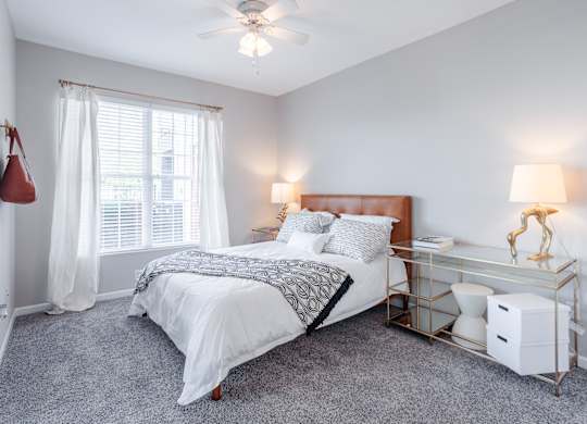 A bedroom with a bed, nightstand, and window.