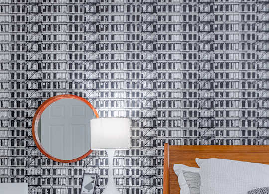 A bedroom with a bed, chair, and a mirror.
