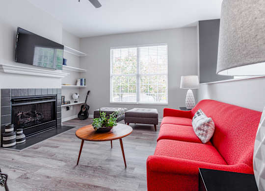 A living room with a red couch and a fireplace.