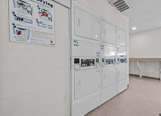 a white kitchen with a row of white refrigerators in it