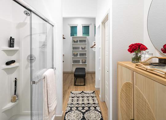 a bathroom with a glass shower stall and a black and white rug