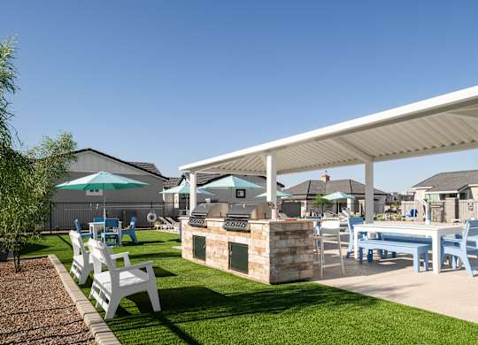 A white pergola is over a table and chairs.
