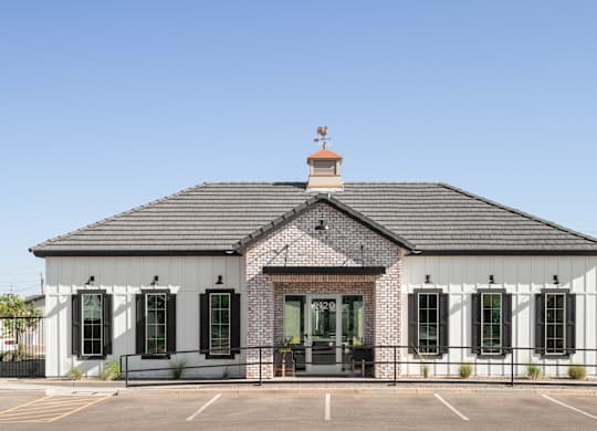 A white building with black shutters and a brick chimney.