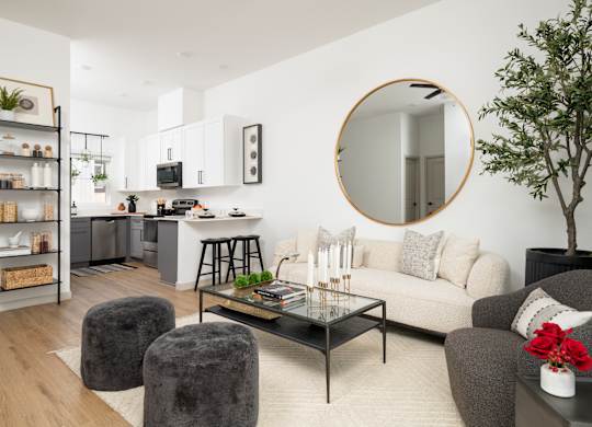 A modern living room with a grey couch, a coffee table, and a round mirror on the wall.