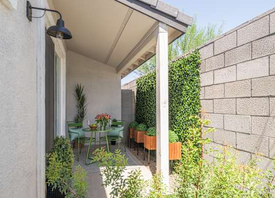 A patio with a table and chairs is covered by a white awning.