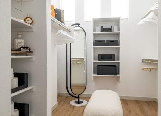 A white chair sits in a room with white walls and wood floors.