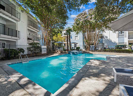 A swimming pool surrounded by trees and buildings.