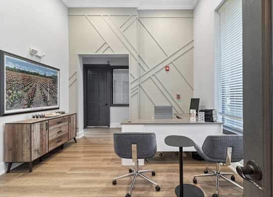 an office with a desk and chairs and a wall with a tv