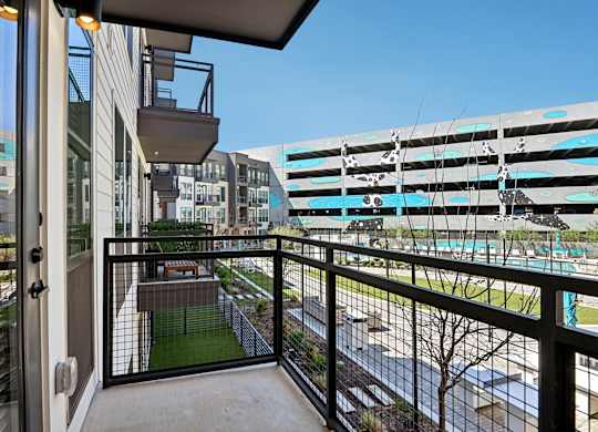 A balcony with a view of a pool and buildings.