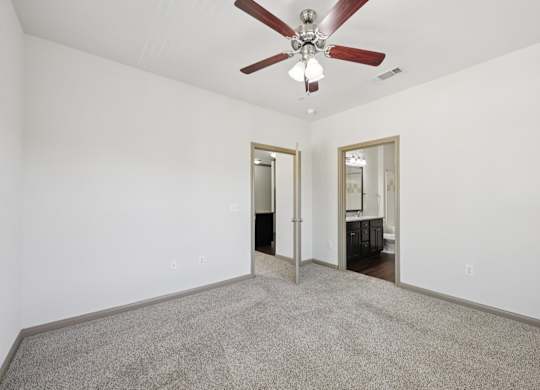 A room with a ceiling fan and carpeted floor.