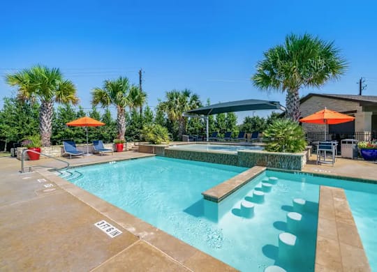 A pool with a water slide and a few chairs.