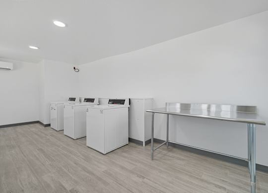 A white room with a table and a couple of washing machines.