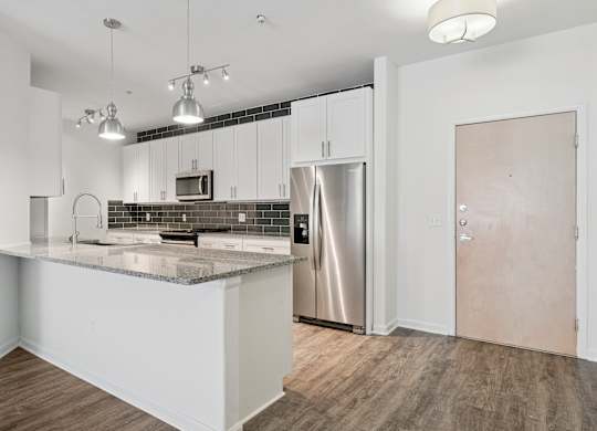 A kitchen with a refrigerator, microwave, and oven.