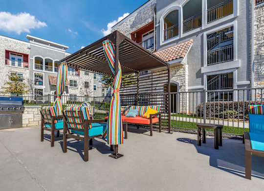 A patio with a striped awning and striped chairs.