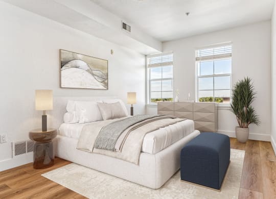 a white bedroom with a bed and a blue ottoman