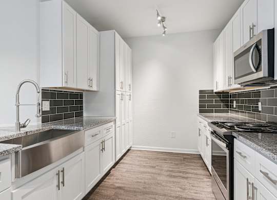 A kitchen with white cabinets and a black stove top.