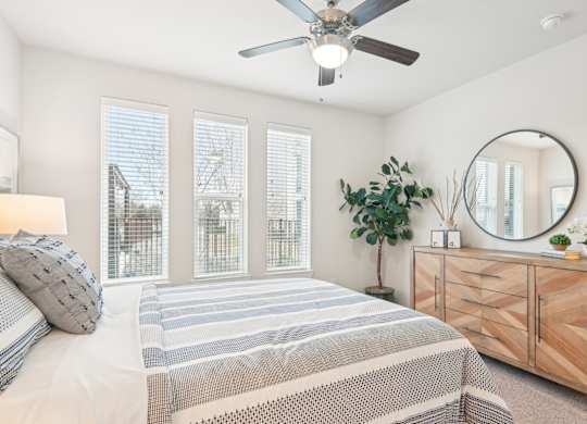 A bedroom with a bed, a dresser, and a ceiling fan.