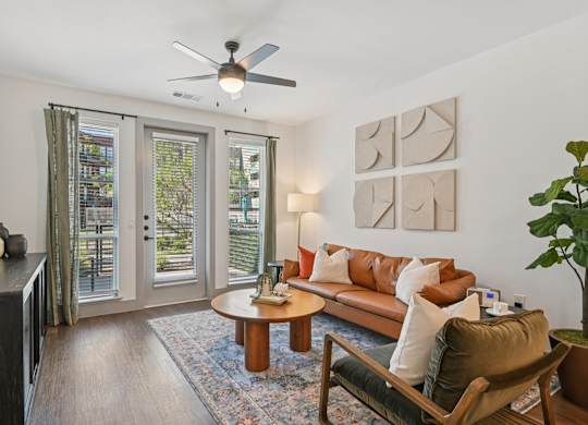 A living room with a brown couch, a coffee table, and a ceiling fan.