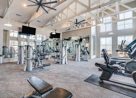 A gym with a variety of equipment including treadmills, weights, and a bench.