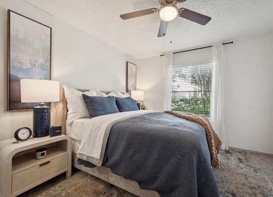 A bedroom with a bed, nightstand, and window.