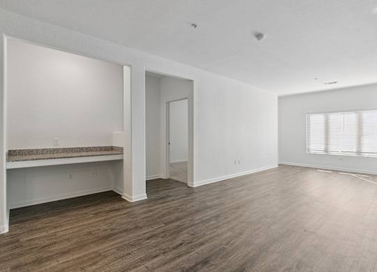 A large empty room with wooden floors and white walls.