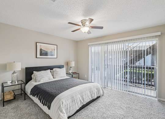 A bedroom with a bed, nightstands, and a ceiling fan.